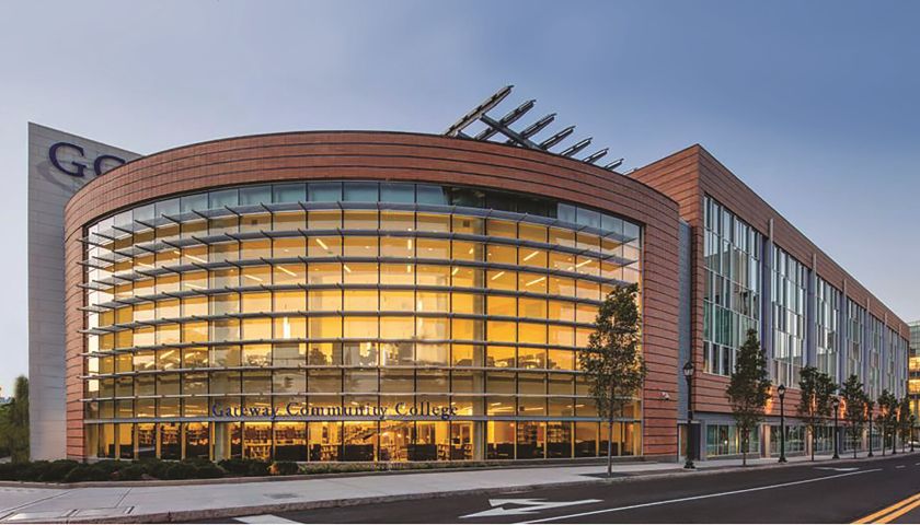 A photo of Gateway Community College exterior. The front area is entirely glass and shines with a yellow glow from interior lights.