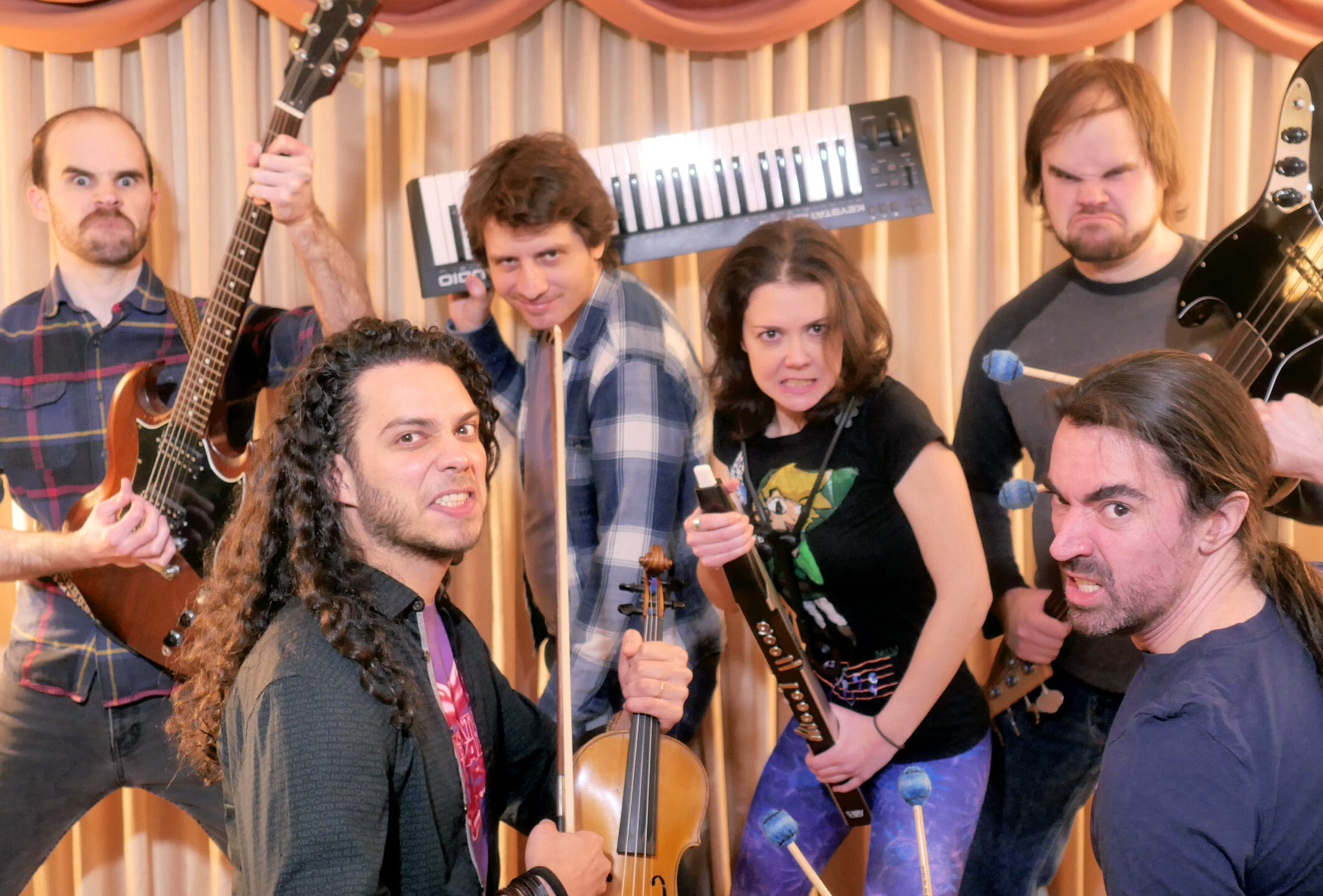 The band DiscoCactus stands in a fighting pose holding their instruments as pretend video game weapons