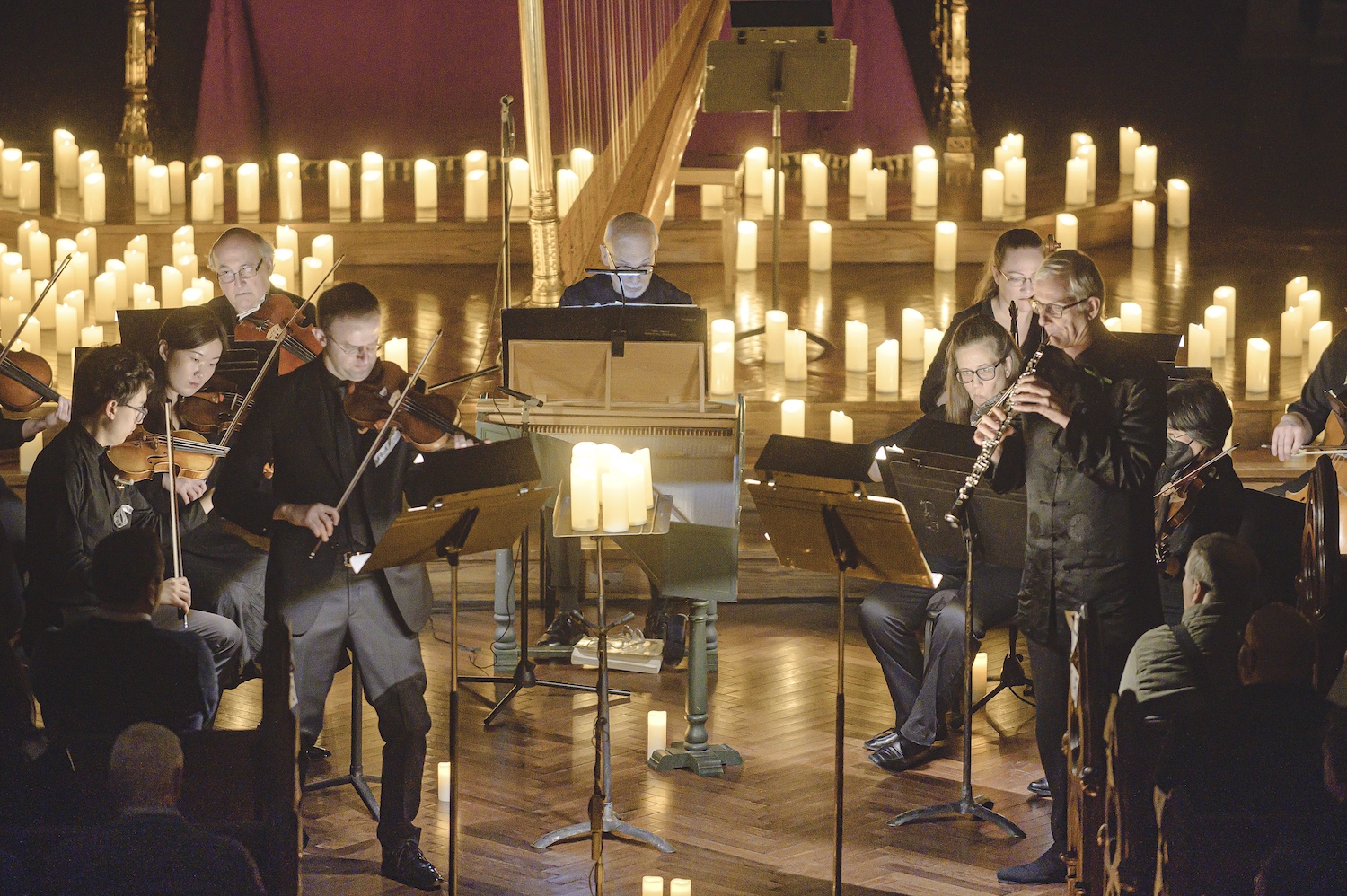 Members of an orchestra play surrounded by hundreds of pillar candles